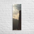 The Sunlit Shelf, tall wrapped canvas print: a lone figure on a sun-warmed rock shelf beside a towering cliff wall.
