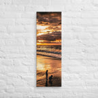 At the Water's Edge, tall wrapped canvas print: two figures on wet sand at the water's edge under a blazing golden sunset.