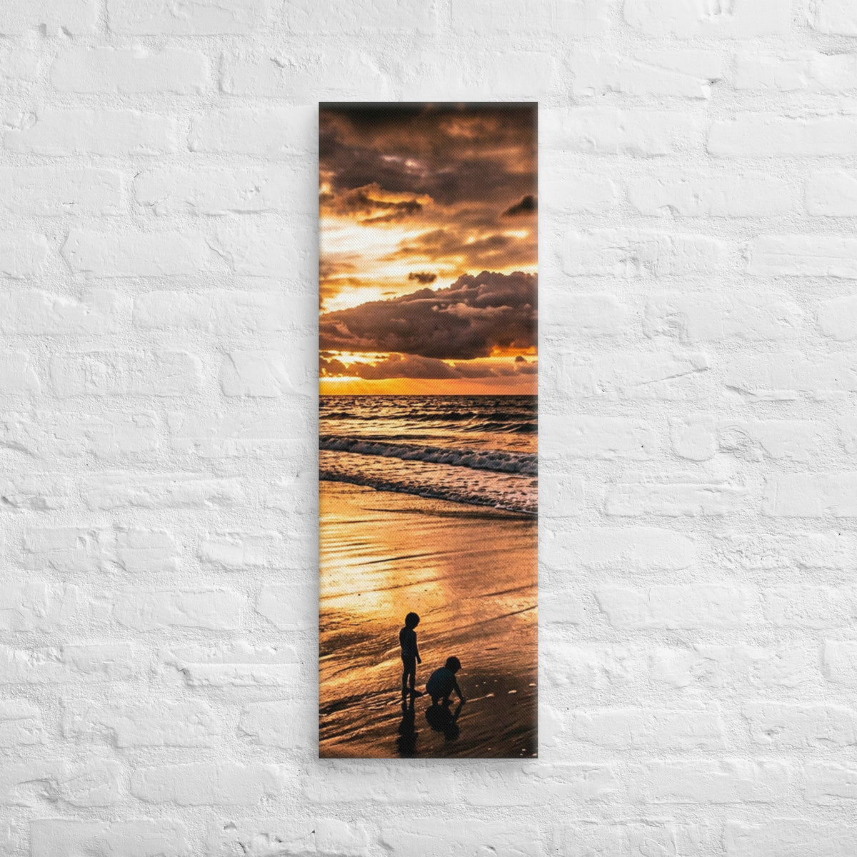 At the Water's Edge, tall wrapped canvas print: two figures on wet sand at the water's edge under a blazing golden sunset.