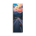 The Rose Lit Summit, tall wrapped canvas print: a serpentine road through a valley toward snow peaks under rose-pink sunset clouds.