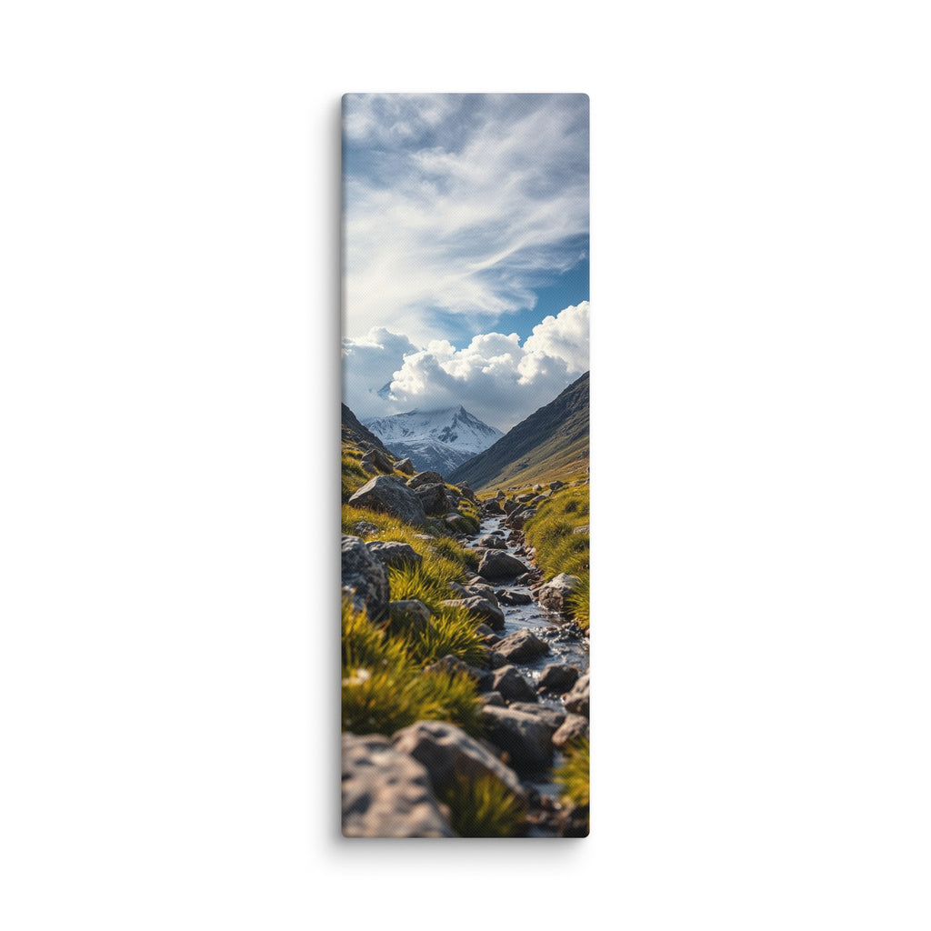 Where The Snow Begins, tall wrapped canvas print: a stream crossing a green alpine meadow toward snow-capped peaks under swirling clouds.