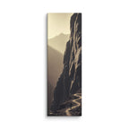 The Ascending Light, tall wrapped canvas print: a lone figure on a winding cliff path as golden light climbs a mountain ridge.