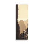 The Golden Defile, tall wrapped canvas print: a lone figure on a ridge path between dark cliffs filled with golden haze and light.