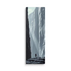 A Pale Immensity, tall wrapped canvas print: a lone figure on dark rocks before a vast pale ice cliff with shafts of light.