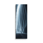 Blue Interval, tall wrapped canvas print: a small figure walking beneath towering blue-black ice curtains with a shaft of white light breaking through.