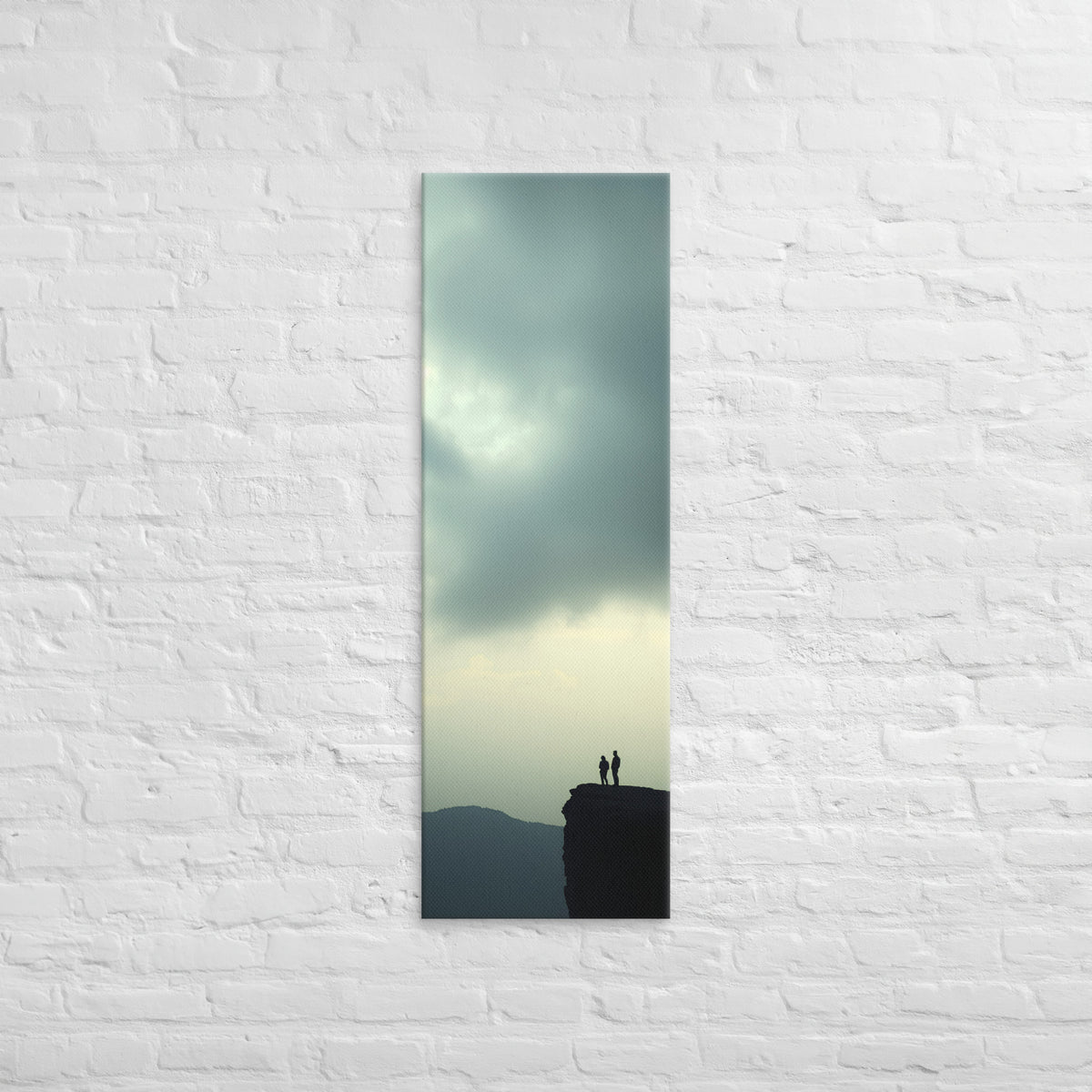Two at the Horizon, tall wrapped canvas print: two figures at the edge of a cliff under a vast pale grey-green sky, distant mountain ridges.