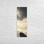 A Summit in Light, tall wrapped canvas print: a lone figure atop a dark rocky summit with radiant light breaking through clouds.