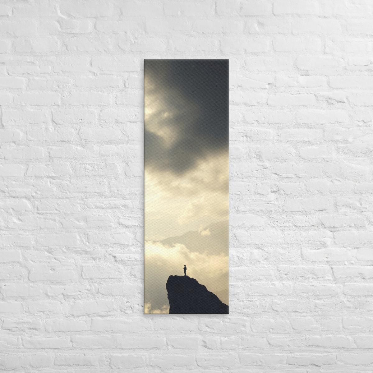 A Summit in Light, tall wrapped canvas print: a lone figure atop a dark rocky summit with radiant light breaking through clouds.