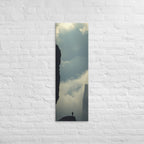 Between the Dark Walls, tall wrapped canvas print: a solitary figure on a rock fin between two sheer dark cliff walls, mist in the gorge.