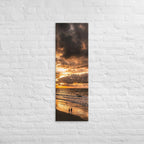 Two at the Tide, tall wrapped canvas print: two figures on wet sand under a fiery orange sunset over the sea.