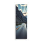 A Doorway Of Light, tall wrapped canvas print: a winding road through a rocky mountain pass with the sun bursting through clouds between peaks.