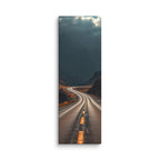 Beneath The Dark Summit, tall wrapped canvas print: a winding road through a dark mountain valley beneath brooding blue-grey peaks.