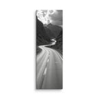 Silver Through Stone, tall wrapped canvas print: a black-and-white serpentine road winding through a rocky mountain gorge beneath dramatic clouds.