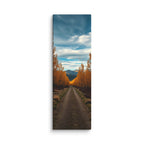 The Quiet Miles, tall wrapped canvas print: a straight road through a tunnel of golden autumn trees toward distant mountains.