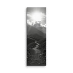 The Silent Ascent, tall wrapped canvas print: a black-and-white winding mountain path climbing toward sunlight breaking through clouds.