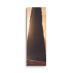 Before The First Light, tall wrapped canvas print: a lone figure before a colossal dark monolith with golden dawn light behind it.