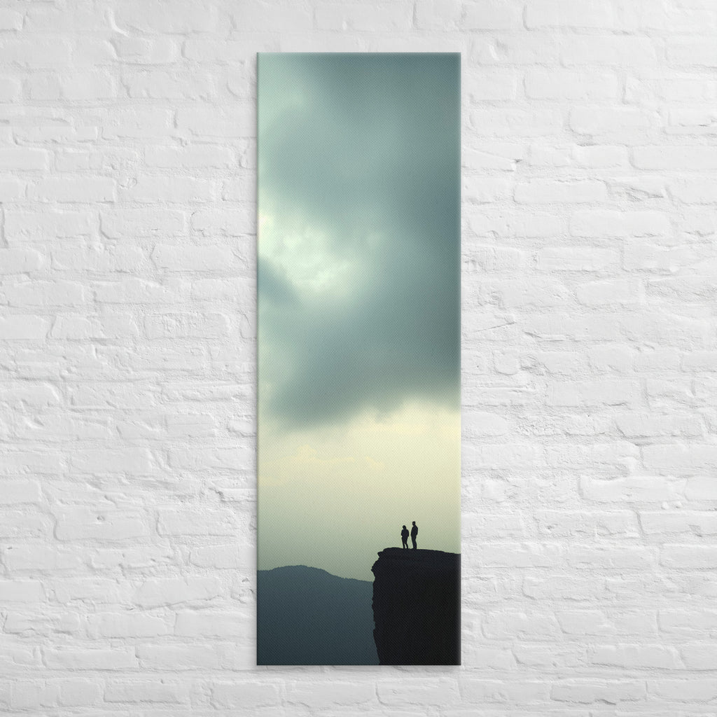 Two at the Horizon, tall wrapped canvas print: two figures at the edge of a cliff under a vast pale grey-green sky, distant mountain ridges.