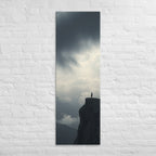 Where the Clouds Break, tall wrapped canvas print: a lone figure on a high cliff as dark clouds split open with light behind.