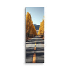 An Avenue Of Gold, tall wrapped canvas print: a straight road flanked by tall golden poplars under a clear blue sky, a forested mountain behind.