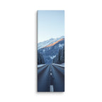 The Last Warm Ridge, tall wrapped canvas print: a road between snowy pines toward a snow peak catching the last warm alpenglow.