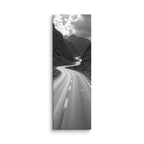 Silver Through Stone, tall wrapped canvas print: a black-and-white serpentine road winding through a rocky mountain gorge beneath dramatic clouds.