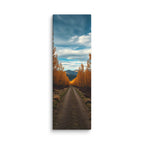 The Quiet Miles, tall wrapped canvas print: a straight road through a tunnel of golden autumn trees toward distant mountains.