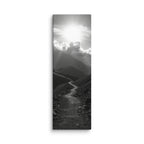 The Silent Ascent, tall wrapped canvas print: a black-and-white winding mountain path climbing toward sunlight breaking through clouds.
