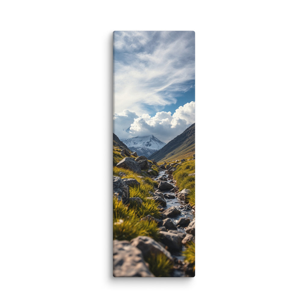 Where The Snow Begins, tall wrapped canvas print: a stream crossing a green alpine meadow toward snow-capped peaks under swirling clouds.