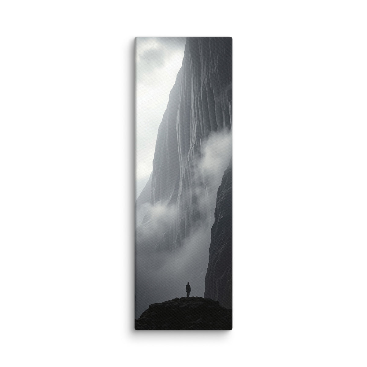 Between Earth And Cloud, tall wrapped canvas print: black-and-white image of a lone figure on a dark outcrop between mist-shrouded ice cliffs.