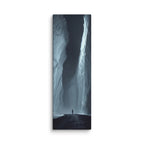 The Dark Reach, tall wrapped canvas print: a lone figure on dark ice between towering ice walls with light falling down one face.